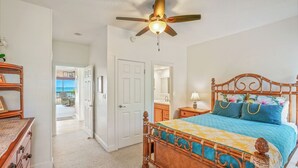 A bedroom with a wooden bed, a ceiling fan, and a view of the outside. - "Magical View" oceanfront condo Lae Nani #521 (Kapaa)