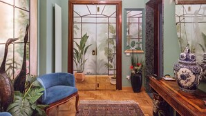 A room with a blue armchair, a wooden cabinet with a decorative vase, and a door with a geometric pattern. - It is time to dream enjoying the steam  bath  listening lovely music  (Roma)