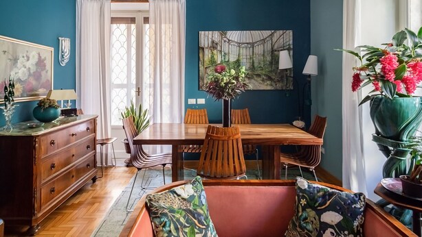 A dining area with a wooden table and chairs, a vase with flowers, and a painting on the wall. - It is time to dream enjoying the steam  bath  listening lovely music  (Roma)