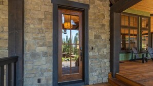 A stone exterior with a wooden door, a porch with wooden steps, and a view of a backyard. - NEW - Truckee Luxury Retreat - Remote Work Friendly - Sleeps 10+ (Truckee)