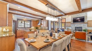 A spacious kitchen with wooden beams, a stone fireplace, and a dining area with a long table set for six. - NEW - Truckee Luxury Retreat - Remote Work Friendly - Sleeps 10+ (Truckee)