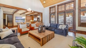 A spacious living room with a wooden ceiling, a large window with a view of a snowy landscape, a fireplace, and a cozy seating area with a coffee table. - NEW - Truckee Luxury Retreat - Remote Work Friendly - Sleeps 10+ (Truckee)