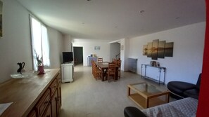 Ein geräumiger Wohnbereich mit Esstisch, Stühlen, einer Couch und einem Fernseher.
