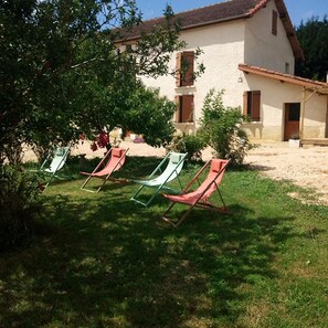 Ein Haus mit Garten. Vier Stühle stehen im Garten.