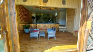 Eine Holzterrasse im Freien mit Korbmöbeln und einer kleinen Bar.
