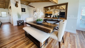 Een ruime eethoek met een houten tafel en bank, omringd door witte wanden en houten vloeren.