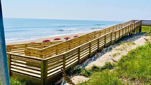 A wooden boardwalk leading to a beach with umbrellas. - BIS-Duck Resort - Spacious 2BR/2BA with Pool, Courtyard, Ocean View (Duck)