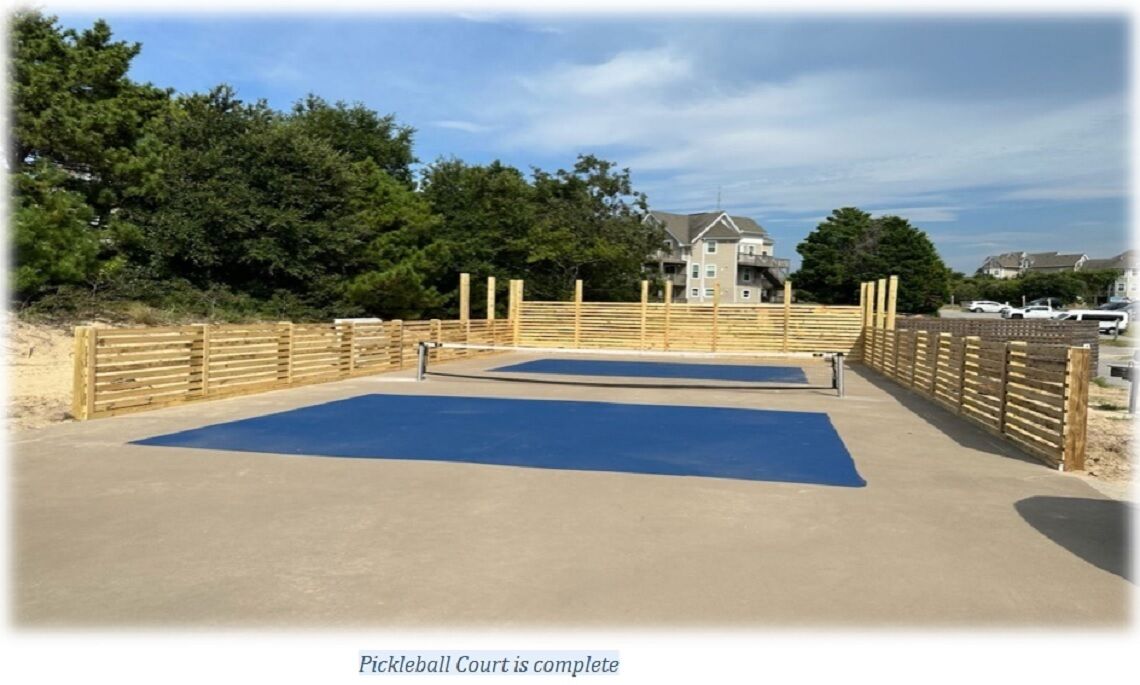 A concrete deck with two blue mats, surrounded by a wooden fence, and a building in the background.