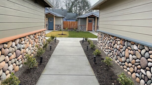 A pathway leading to a row of cabins with stone walls and small plants. - Riverside Cabin 5 - (Brand New Construction) (Grants Pass)