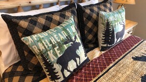 A bed with a wooden headboard, two patterned pillows, a quilt, and a bedside lamp. - Riverside Cabin 5 - (Brand New Construction) (Grants Pass)