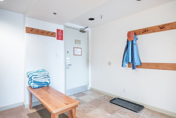Un pasillo con un banco de madera, un perchero y una puerta con un cartel.