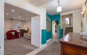 A hallway with a red armchair, a beige sofa, and a wooden dresser.