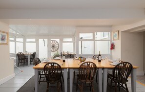 A dining area with a wooden table set for six, surrounded by chairs.
