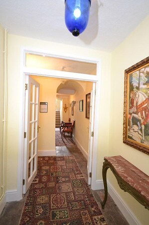 A hallway with patterned carpet, a bench, and a framed painting on the wall.