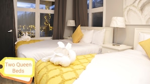 Camera d'albergo con due letti queen, un comodino, una lampada e una finestra con tende.