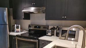Una cucina moderna con elettrodomestici in acciaio inossidabile, forno a incasso, microonde e lavandino.