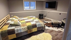 Un dormitorio con cama, ventana, televisor y calentador.