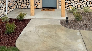 A building with a stone facade, a blue door, and a welcome mat. - Riverside Cabin 6 (Grants Pass)