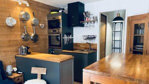 Eine moderne Küche mit Holzelementen, einer zentralen Kochinsel und einem Essbereich mit einem Holztisch.