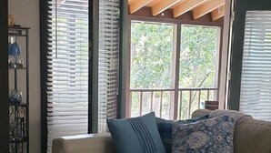 A living room with a beige sofa, two pillows, a tray table with a mug, and a window with blinds. - Pool Side Getaway With Hot Tub at Tan-Tar-A Estates! Bordering Margaritaville! (Osage Beach)