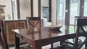 A dining area with a wooden table and chairs, a decorative wall piece, and a patterned rug. - Pool Side Getaway With Hot Tub at Tan-Tar-A Estates! Bordering Margaritaville! (Osage Beach)