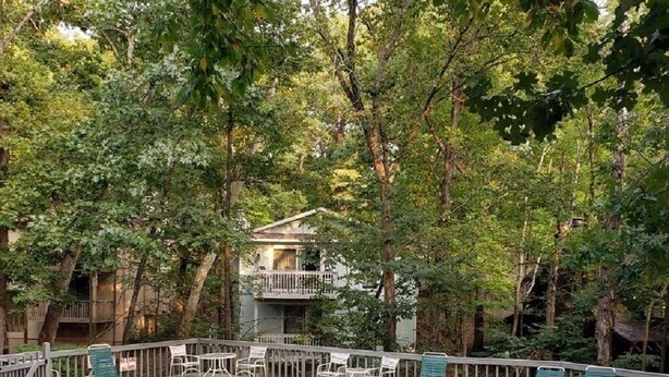 A swimming pool surrounded by trees, with lounge chairs and a building in the background. - Pool Side Getaway With Hot Tub at Tan-Tar-A Estates! Bordering Margaritaville! (Osage Beach)