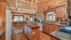 Una cocina amplia con armarios de madera, una isla central y un comedor con sillas y una mesa.