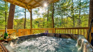 Un jacuzzi rodeado por una terraza de madera con vistas a un bosque.