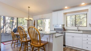 Une cuisine moderne avec des meubles blancs, un plan de travail en granit et un coin repas doté de chaises en bois.
