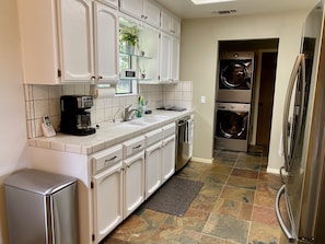 Kitchen area with coffee maker, trash bin, and access to laundry facilities.