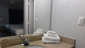 A bathroom with a sink, mirror, and stacked towels. - Park View Inn (Greensboro)