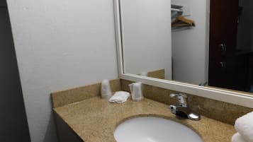 A bathroom with a granite countertop, a white sink, a mirror, and a towel rack.