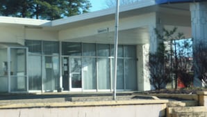 A building with a clear sign reading "Clearance 9-0" and a flagpole with an American flag. - Park View Inn (Greensboro)