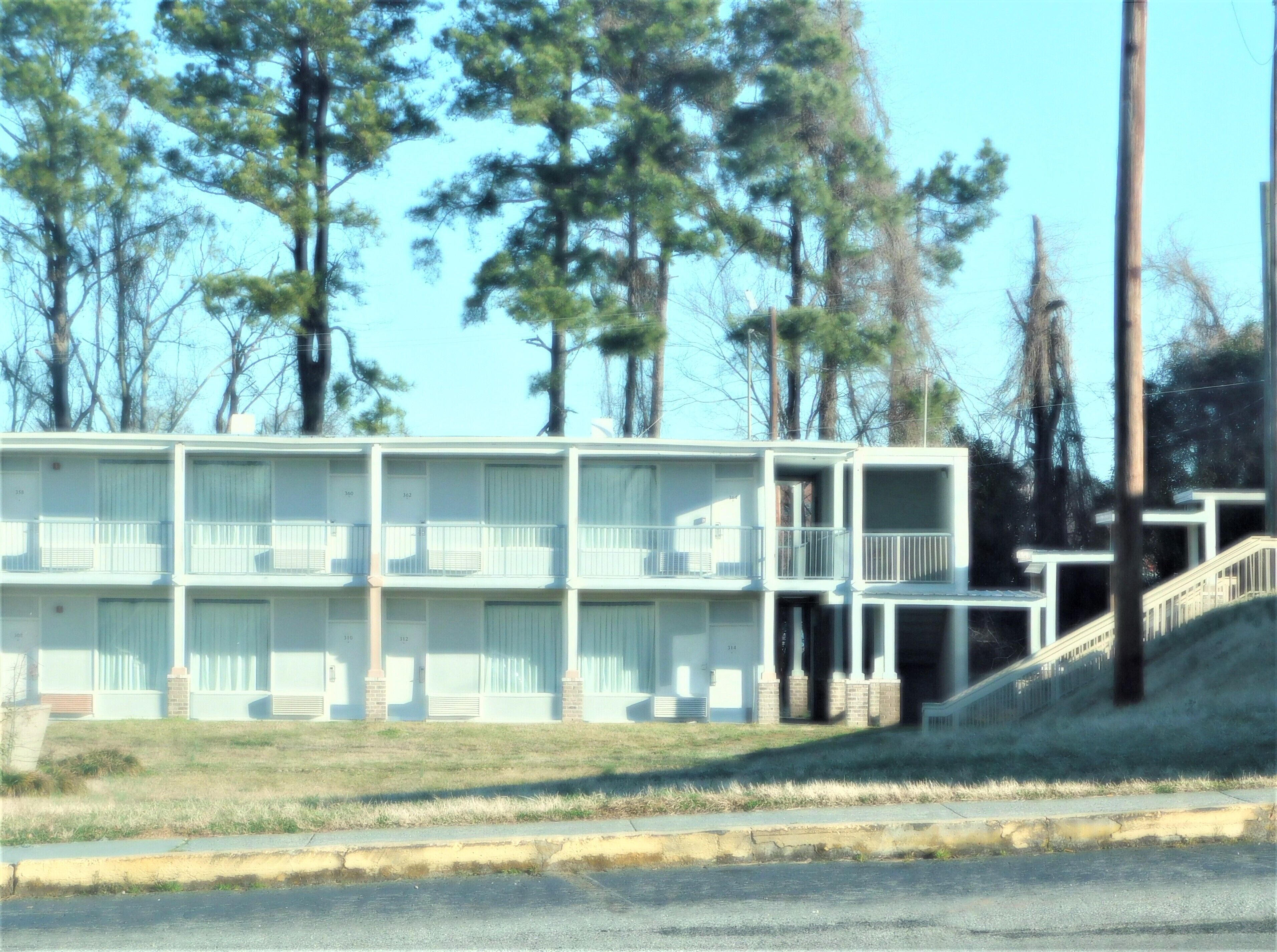 A motel with multiple floors, balconies, and a staircase leading to the entrance.