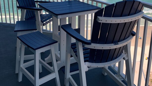 A balcony with Adirondack chairs and a table, overlooking a beach and the ocean. - Oceanfront 3-bedroom condo – 17SE - Beach Access, Pool & Hot tub! Owner Managed (Daytona Beach Shores)