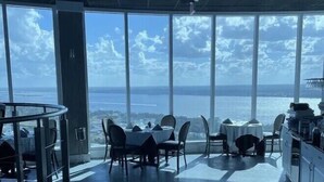 A dining area with large windows offering a view of the sea. - Oceanfront 3-bedroom condo – 17SE - Beach Access, Pool & Hot tub! Owner Managed (Daytona Beach Shores)