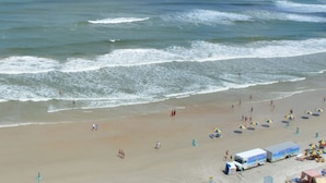 A beach with people, umbrellas, and a lifeguard tower. - Oceanfront 3-bedroom condo – 17SE - Beach Access, Pool & Hot tub! Owner Managed (Daytona Beach Shores)