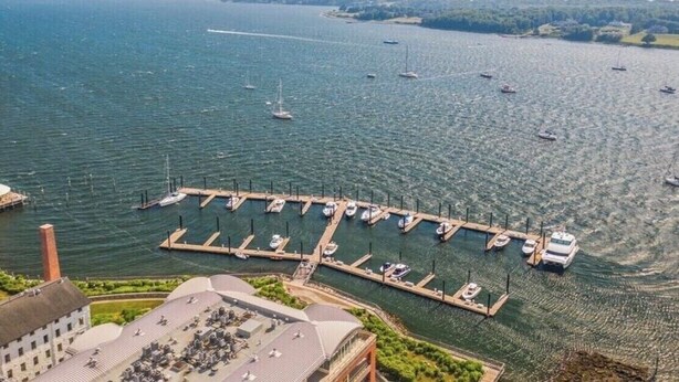 A marina with boats docked at piers, surrounded by water and greenery.