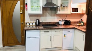 Cuina compacta amb armaris blancs, campana extractora d'acer inoxidable, microones i rentavaixelles.