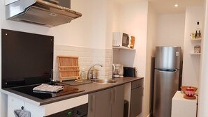 A compact kitchen with a stove, oven, sink, and a stainless steel refrigerator. - Cosy apartment for 1 to 4 people near the CHU (Rouen)
