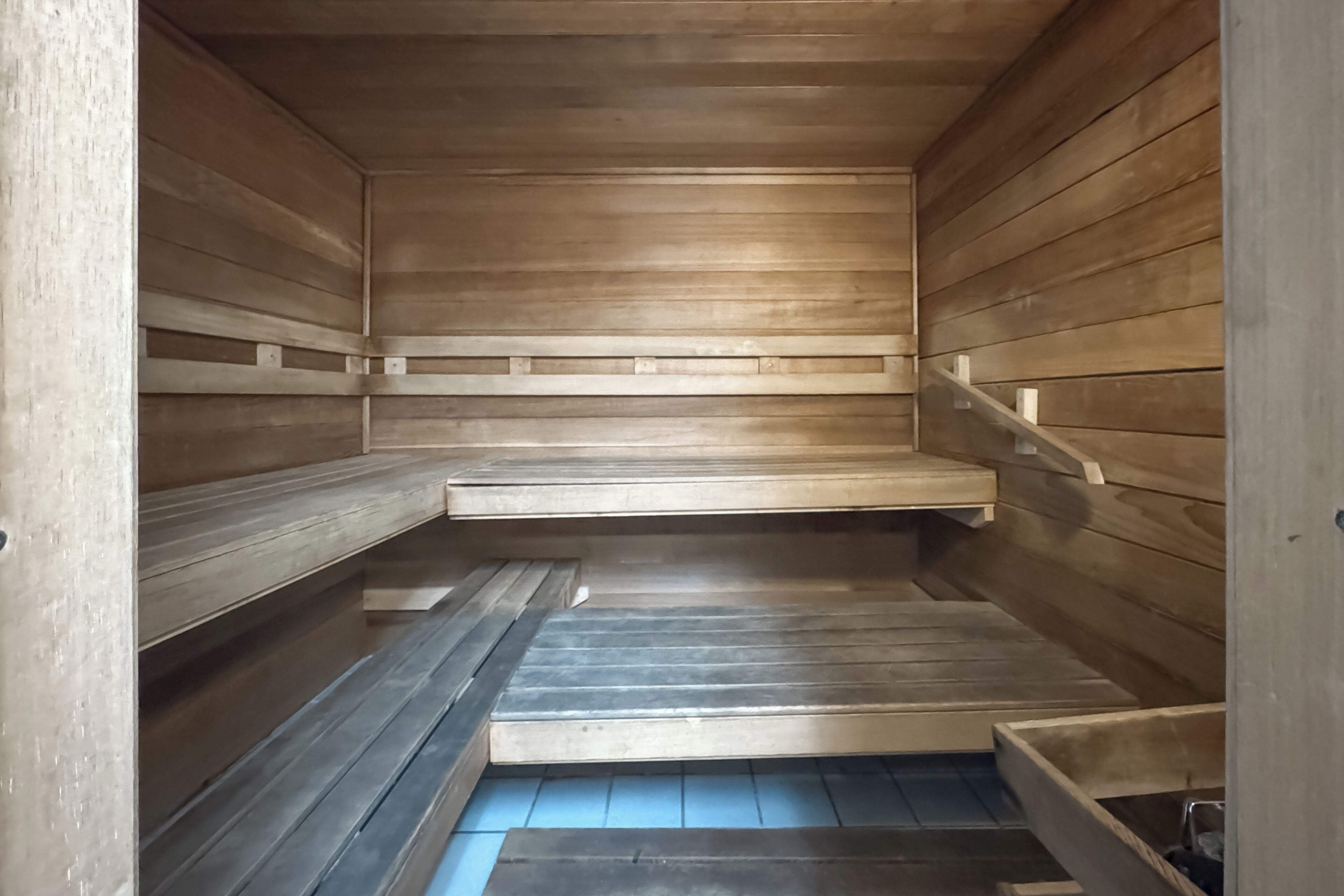 A sauna with wooden benches and a sloped floor.