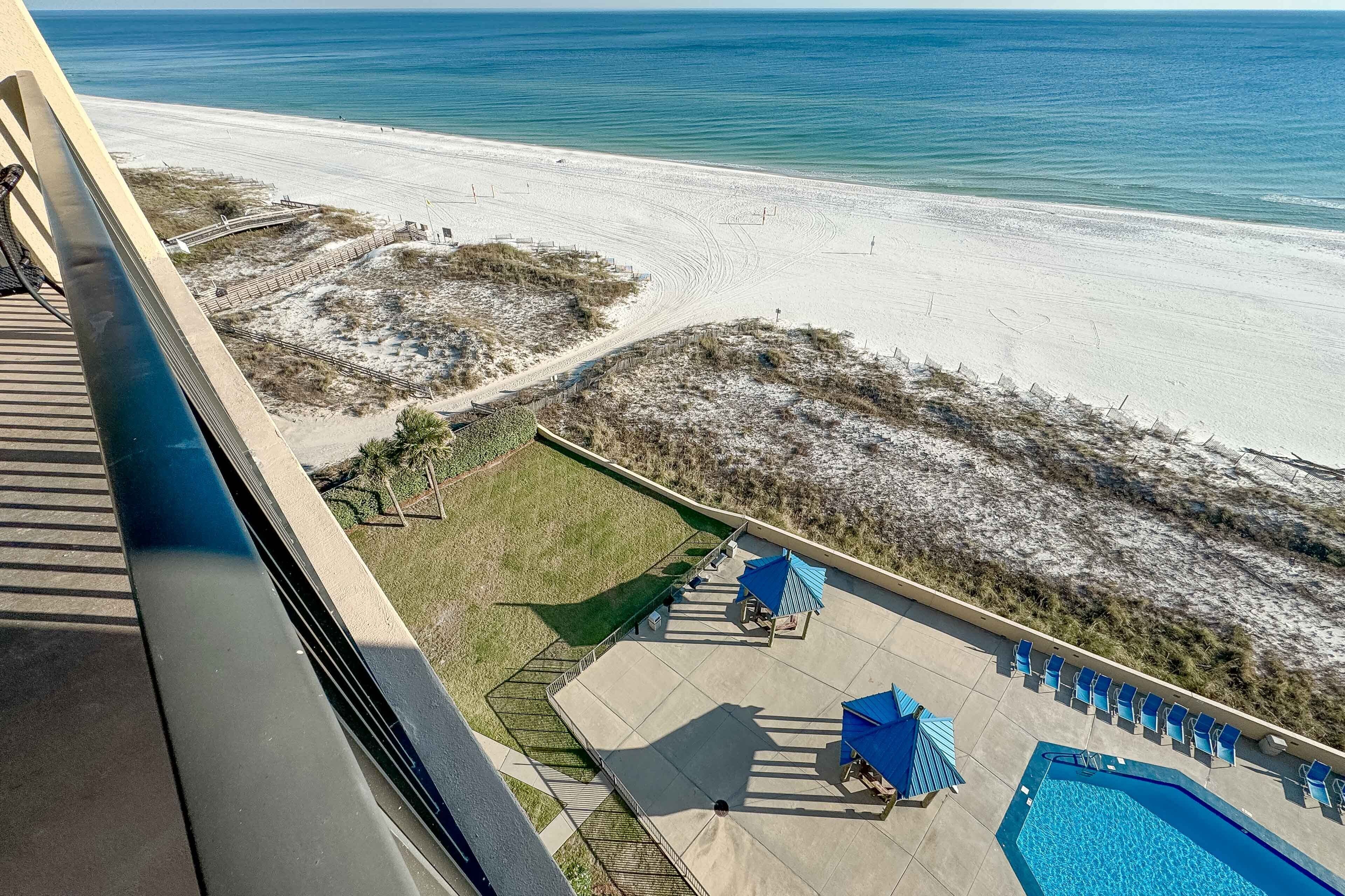 Ein Poolbereich mit Liegestühlen und Sonnenschirmen, Blick auf den Strand und ein Sandweg zum Strand.