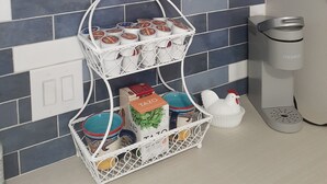 Una cocina con cristalería azul, una cesta blanca con tazas de café Tazo y un gallo de cerámica blanca.