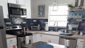 Una cocina moderna con armarios blancos, estufa de acero inoxidable, microondas, tostadora y lavavajillas.