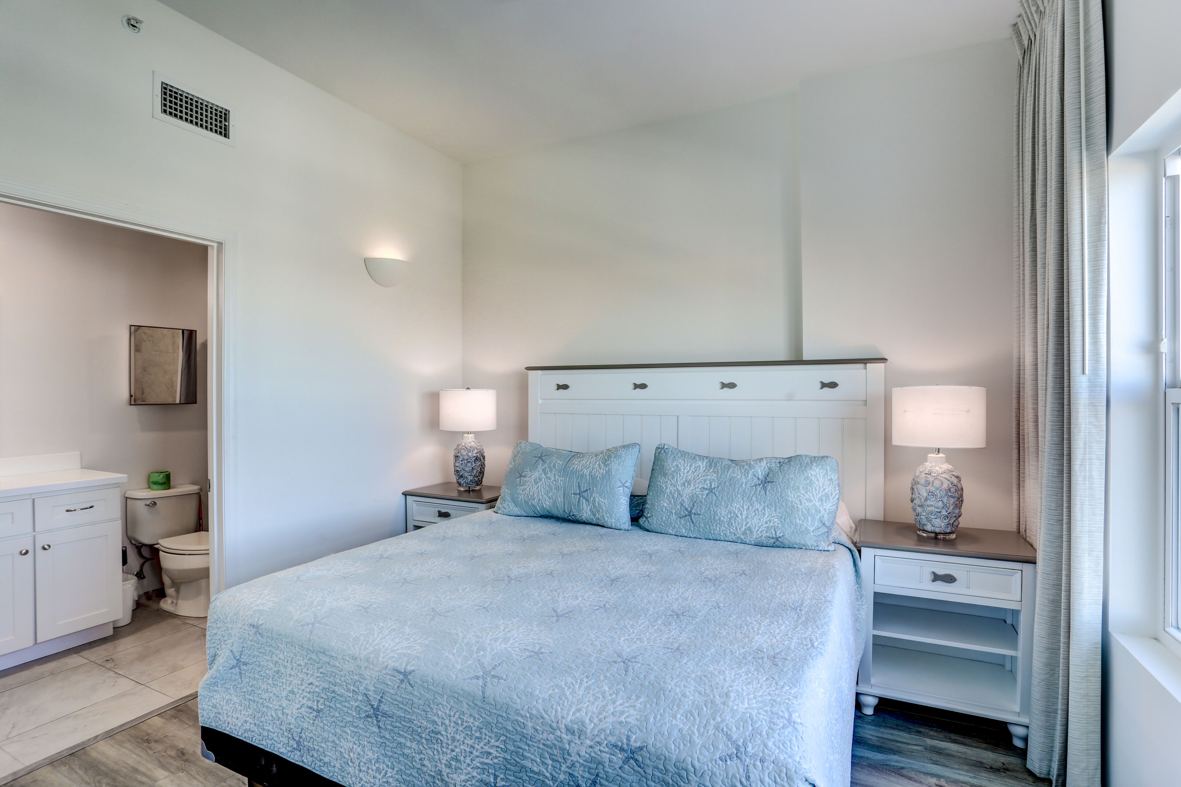 Une chambre à coucher comprenant un lit, des tables de chevet, une commode, une coiffeuse et des toilettes.