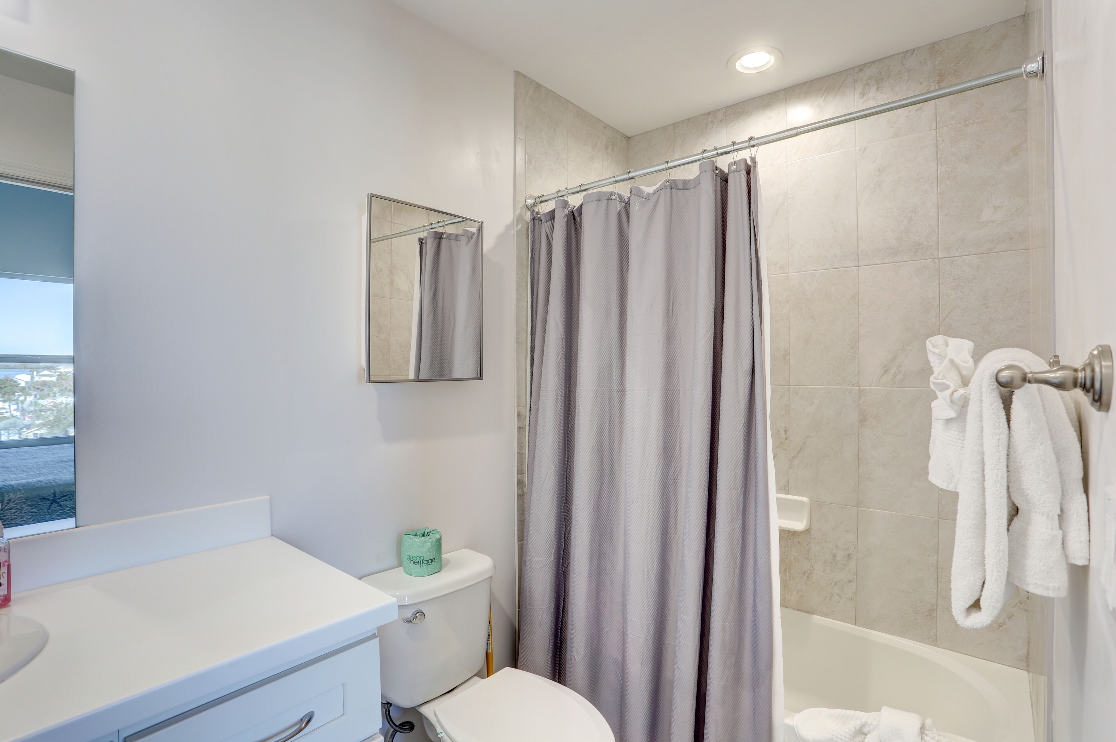 A bathroom with a toilet, a sink, a shower curtain, and a bathtub.