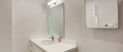 Un baño con lavamanos blanco, espejo e inodoro.