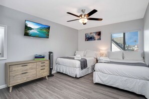 Ein Schlafzimmer mit einem Bett, einem Schminktisch, einem Deckenventilator und einem Fernseher an der Wand.