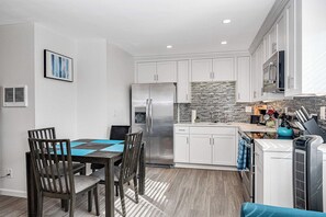 Una cocina moderna con armarios blancos, un refrigerador de acero inoxidable y salpicadero de azulejos.