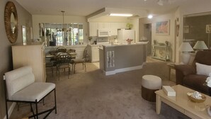 Een woonkamer met een bank, een salontafel en een eethoek met stoelen en een tafel.